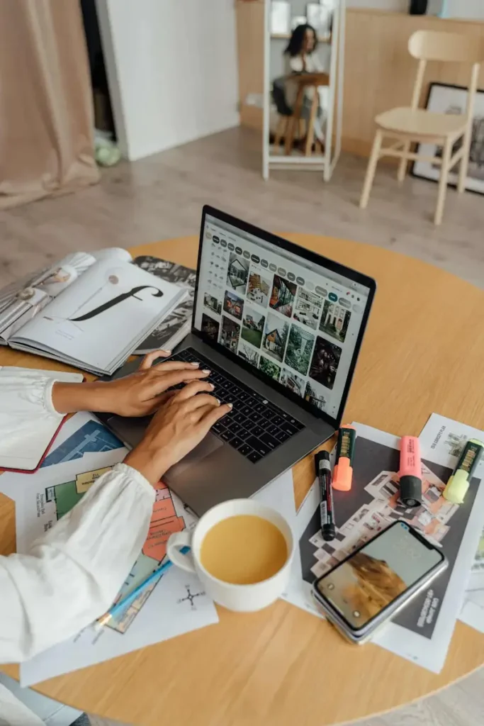 mains de femmes tapant sur le clavier d'un pc portable. sur le bureau il y a une tasse de café et plusieurs feuilles volantes